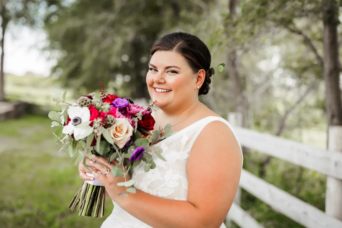 Bride smiling with a jewel-tone bouquet