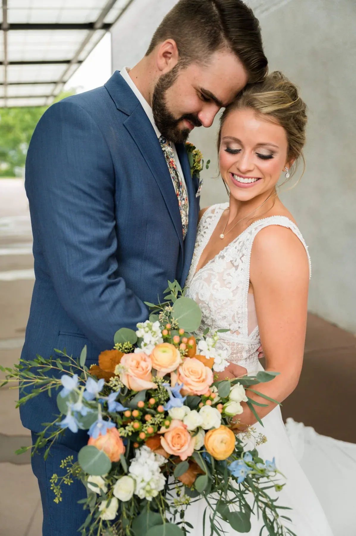 Bride and groom with a peach and blue bouquet