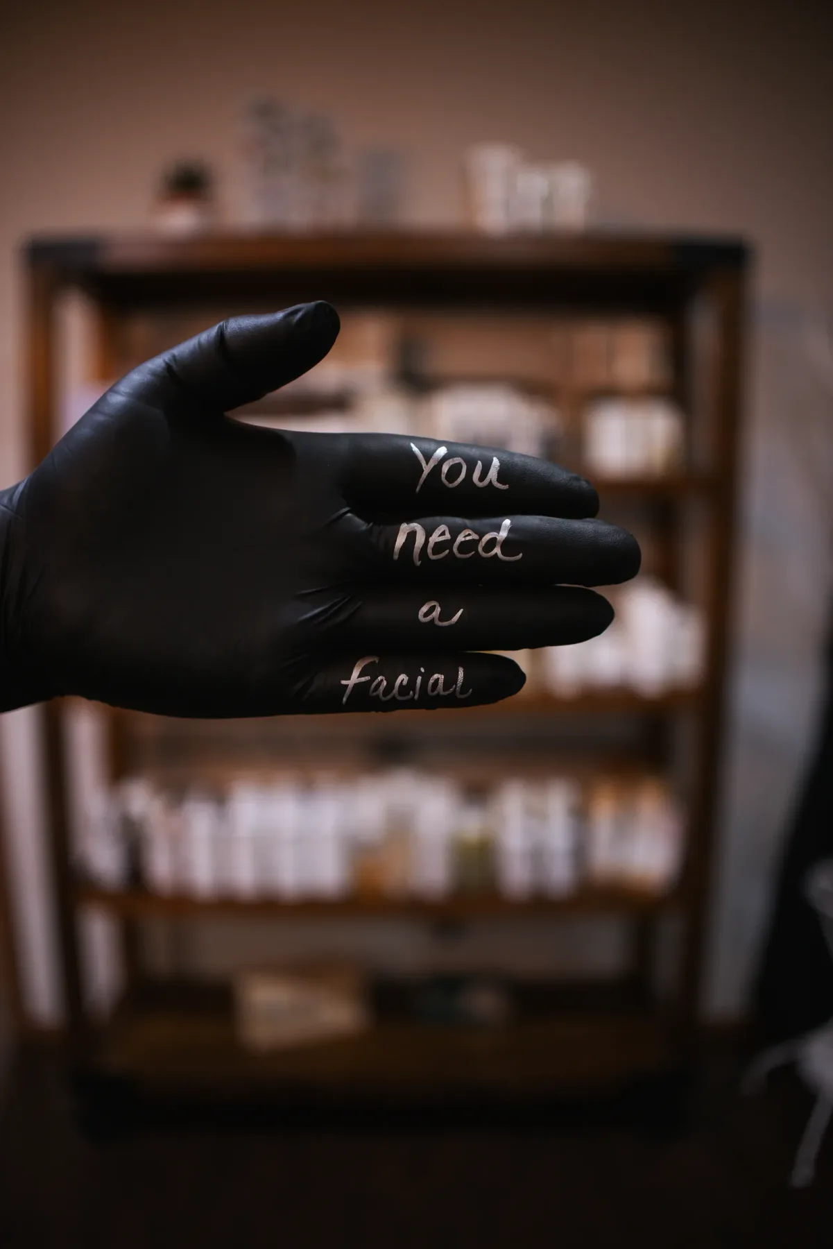A gloved hand reading 'you need a facial' in front of the retail shelves at Evolution of Beauty in Marshall, Minnesota